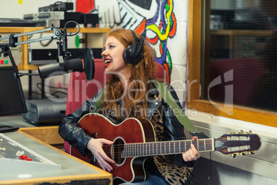Cheerful beautiful singer recording and playing guitar