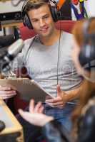 Attractive radio host interviewing a guest holding clipboard