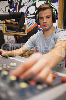Handsome focused radio host moderating turning up volume