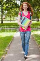 Gorgeous smiling student walking and carrying notebooks