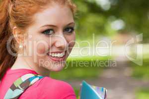 Gorgeous cheerful student holding notebooks looking at camera