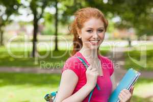 Gorgeous smiling student holding notebooks looking at camera