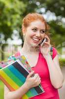 Gorgeous cheerful student holding notebooks phoning