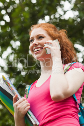 Gorgeous gleeful student holding notebooks phoning