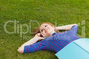 Gorgeous smiling student lying on grass phoning