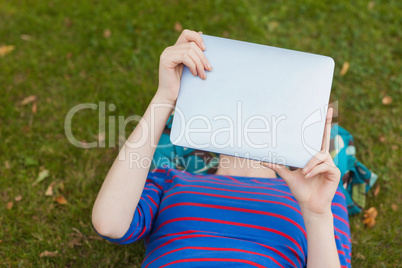 Student lying on grass using tablet