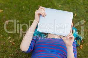 Student lying on grass using tablet