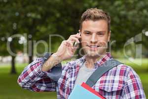 Handsome cheerful student standing and phoning