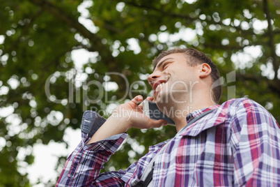 Handsome laughing student standing and phoning