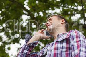 Handsome laughing student standing and phoning