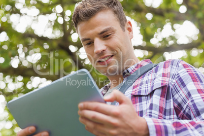 Handsome happy student using tablet