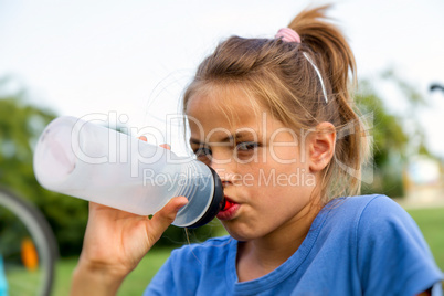 young girl drinking a glass of plastic