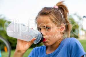 young girl drinking a glass of plastic