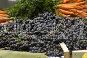 Rote Weintrauben vor orangenen Möhren auf dem Wochenmarkt