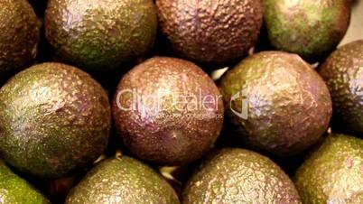 Several brown chicos set of avocadoes are piled
