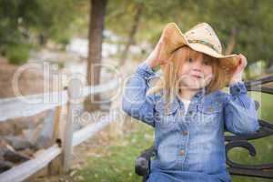 cute young girl wearing cowboy hat posing for portrait outside
