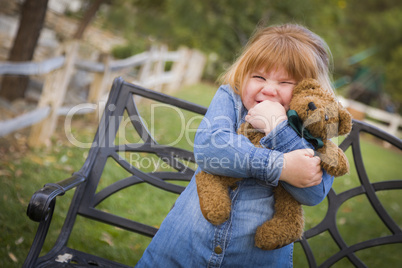 cute smiling young girl hugging her teddy bear outside