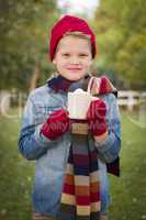 young boy in warm clothing holding hot cocoa mug outside