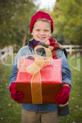 young boy wearing holiday clothing holding christmas gift outsid