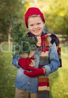 young boy wearing holiday clothing holding small christmas tree