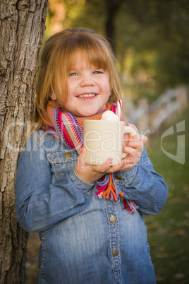 cute young girl holding cocoa mug with marsh mallows outside