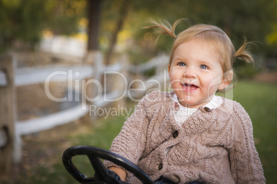 young toddler laughing and playing on toy tractor outside