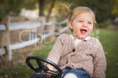 young toddler laughing and playing on toy tractor outside