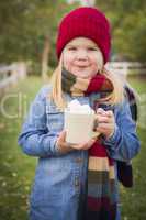 cute young girl holding cocoa mug with marsh mallows outside
