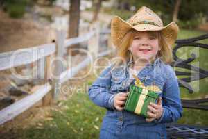 young girl wearing holiday clothing holding christmas gift outsi