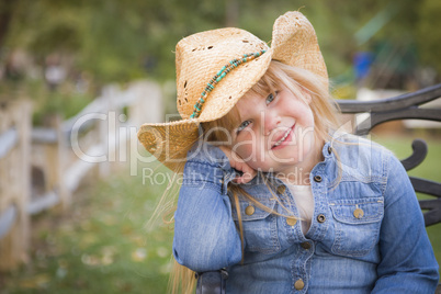cute young girl wearing cowboy hat posing for portrait outside