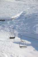 two chair-lift with snowdrift and off-piste slope in sun morning