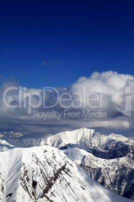 winter snowy sunlit mountains and sky with clouds