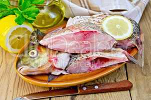 bream raw in a clay plate with a lemon on the board