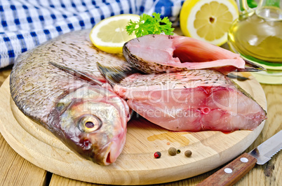 bream raw on a round board with a knife and oil