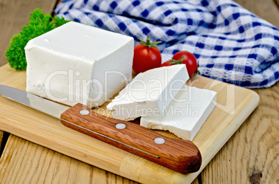 feta cheese on a board with a knife and tomato