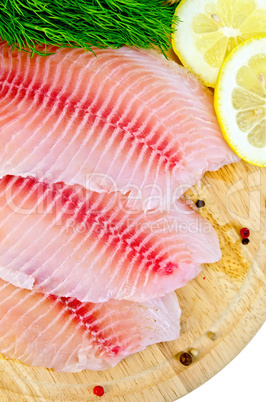 fillets tilapia with lemon and dill on a round board