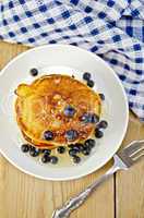 flapjacks with blueberries and a fork on a board