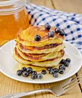 flapjacks with blueberries and a jar of honey on the board