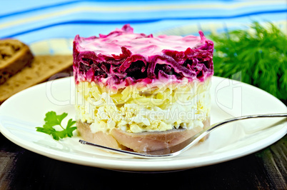 herring with vegetables in white plate with a fork on the board