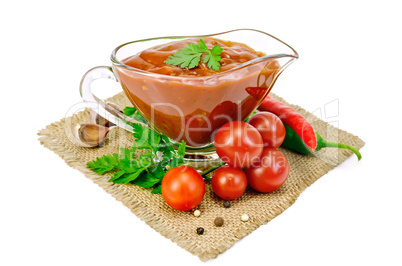 ketchup in a glass gravy boat with vegetables on sacking
