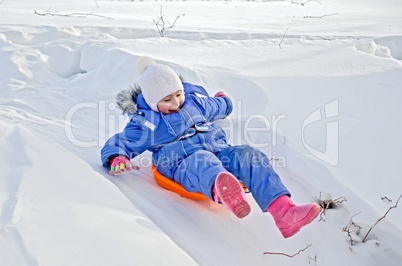little girl on a sled sliding on snow