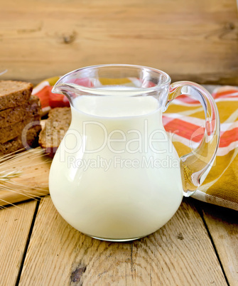 milk in a jug with rye bread and red napkin