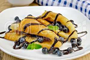 pancakes with blueberries and chocolate syrup on the board