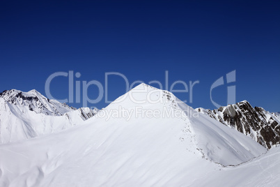 snowy off-piste slope and blue clear sky at nice winter day