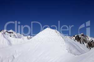 snowy off-piste slope and blue clear sky at nice winter day