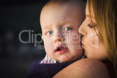 adorable red head infant boy is kissed by his mother