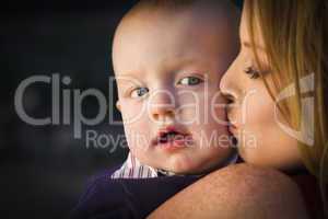 adorable red head infant boy is kissed by his mother