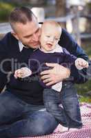 infant boy and young military father play in the park