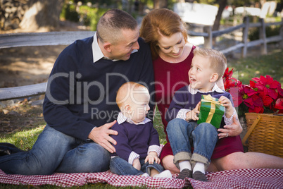 small young family opening christmas gifts in the park