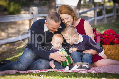 small young family opening christmas gifts in the park